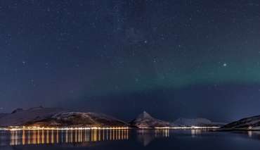 Der Sternenhimmel über einem Fjord in Senja