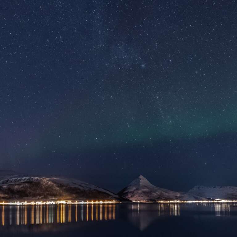 Der Sternenhimmel über einem Fjord in Senja
