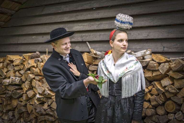 Paar in Fürstenberger Tracht vor Holzstapel