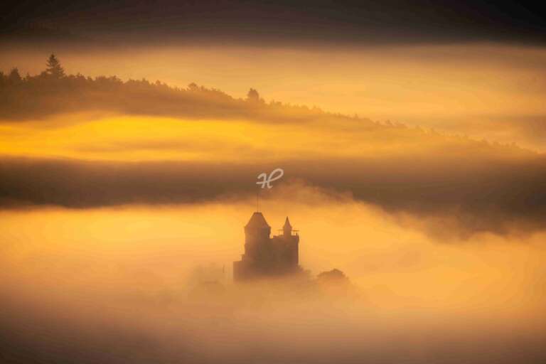 Burg Berwartstein im Morgenlicht, Silhouette der Burgruine Drachenfels im goldenen Nebel
