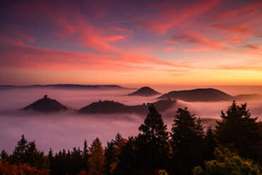 Morgenrot über der Burg Trifels im Pfälzer Wald bei Annweiler mit Nebel in den Tälern