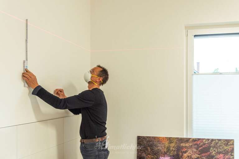 Wandbilder für die DRK Tagespfelge Bühl (Baden), ein Mitarbeiter bestimmt mittels Laser die exakte Position zur Anbringung des Wandbildes im Bad der Pflegeeinrichtung