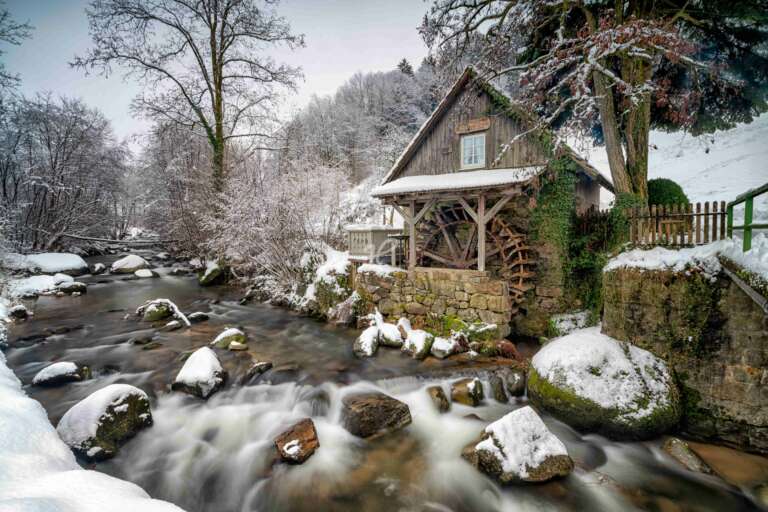 Schwarzwaldmühle im Schnee an einem Bach