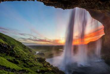 Hinter dem Wasserfall zum Sonnenuntergang in Island