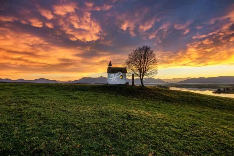 Wolkenstimmung zum Sonnenuntergang über einer kleinen Kapelle bei Riegsee in Bayern