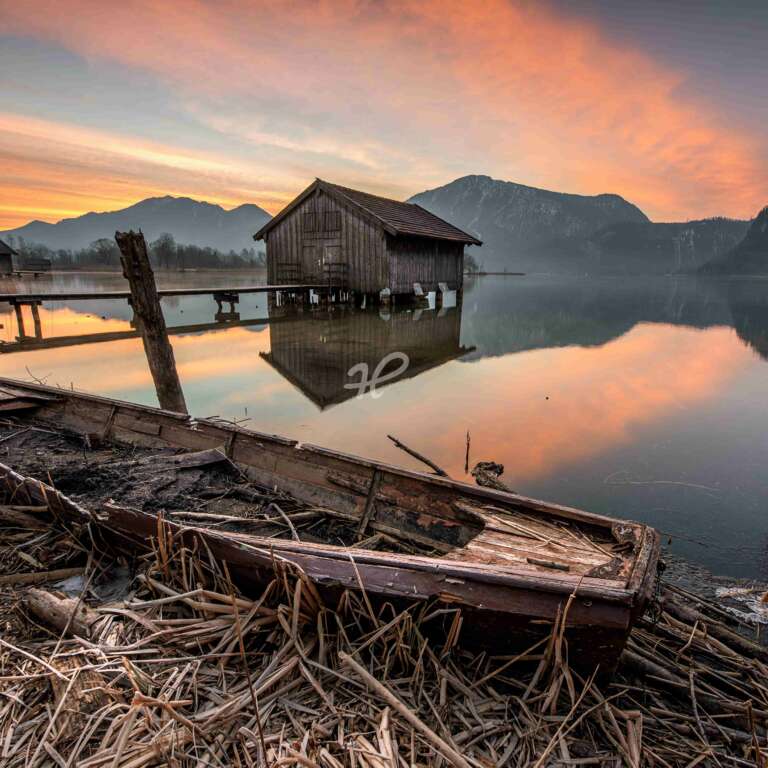 Ein altes Boot am Kochelsee mit Bootshaus zum Sonnenaufgang