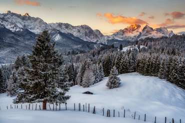 Winterlandschaft mit Neuschnee und einer Hütte in den Bergen in Bayern