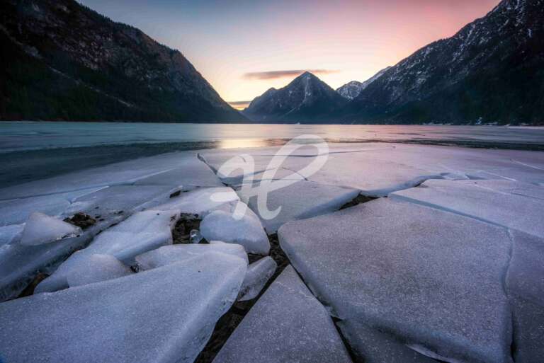 Sonnenaufgang an einem See im Winter mit Eisschollen