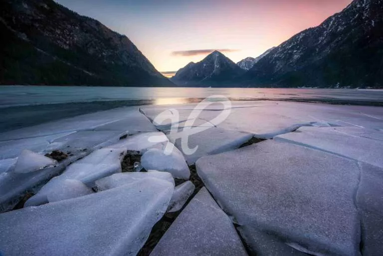 Sonnenaufgang an einem See im Winter mit Eisschollen