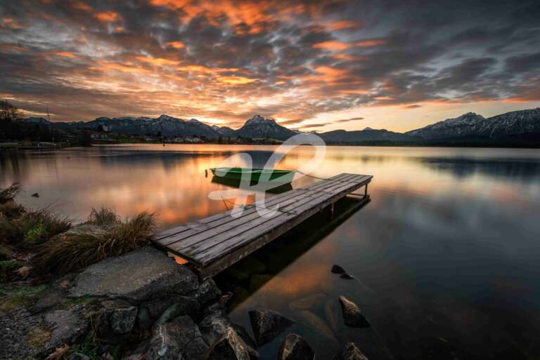 Ein kleines grünes Boot an einem See in Bayern zum Sonnenaufgang