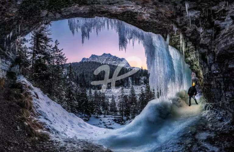 Panorama eines zugefrorenem Wasserfalls im Winter und Eiszapfen zum Sonnenaufgang