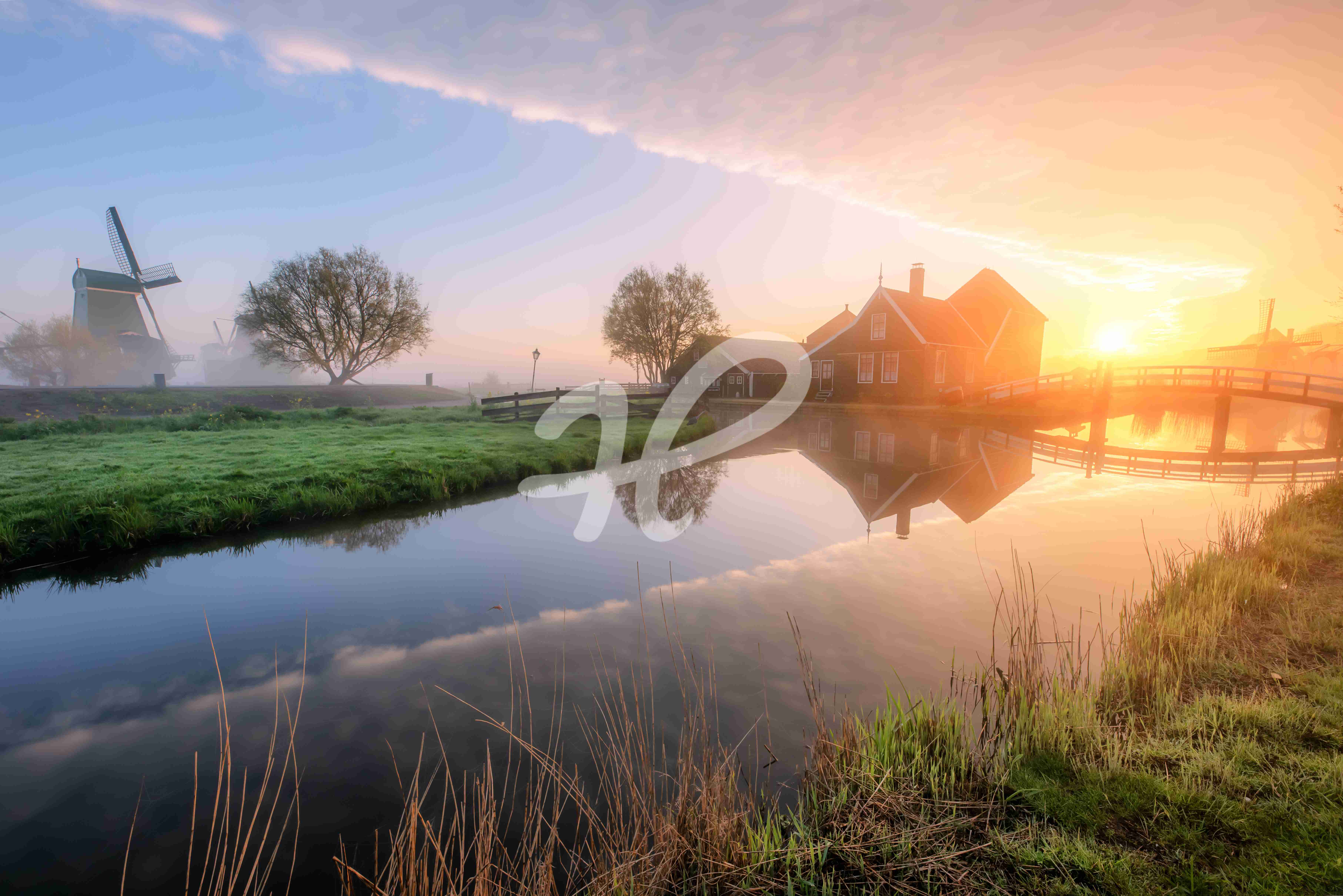 Ein kleines Dorf in den Niederlande zum Sonnenaufgang mit Fluss und Windmühle