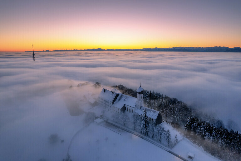 Eine Kirche über dem Nebel im Winter vor dem Sonnenaufgang