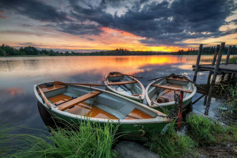 Drei Boote am See zum Sonnenaufgang mit wolken und spiegelung