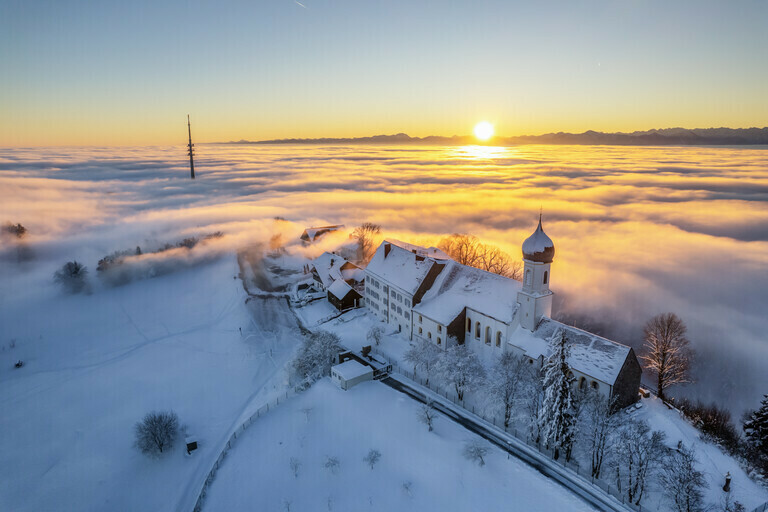Eine Kirche über dem Nebel mit Schnee und Sonnenaufgang