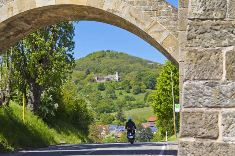 Sandsteinbogen am Leinsweilerhof mit Blick auf den Slevogthof und die Burgruine Neukastel