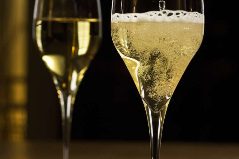 Sekt wird in ein Glas eingschenkt vor dunklem Hintergrund