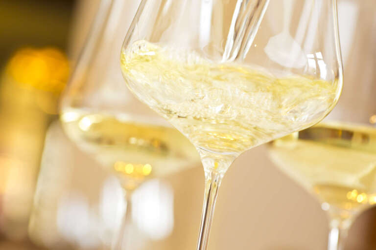 Weißwein wir in ein Glas eingeschenkt