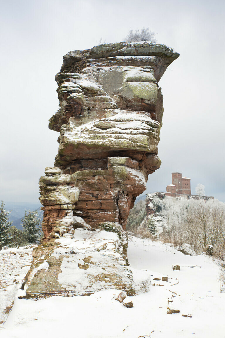 Der verschneite Burgfelsen Anebos – im Hintergrund die Burg Trifels