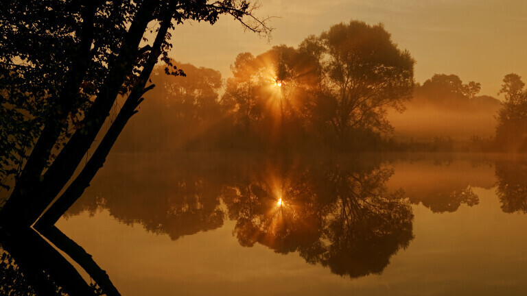 Herbstlicher Sonnenaufgang an einem idyllischen Weiher