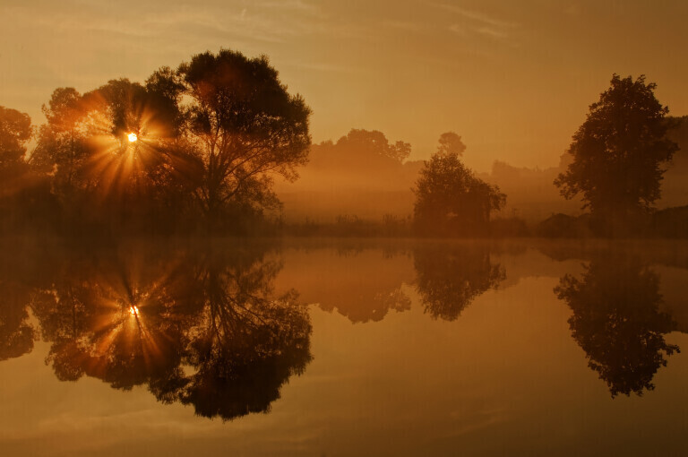 Herbstlicher Sonnenaufgang an einem idyllischen Weiher