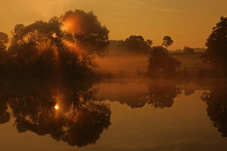 Herbstlicher Sonnenaufgang an einem idyllischen Weiher